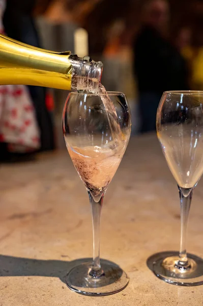 Tasting of rose champagne sparkling wine produced by traditional method in dark underground caves in Champagne, France, close up
