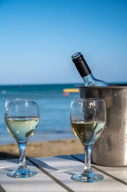 Plaj barında soğuk beyaz şarap içmek, yaz tatilleri, mavi denizde ve kumsalda dinlenmek.
