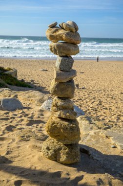 Günbatımında kumlu sahilde, dengeli taşlardan oluşan piramit, Atlantik Okyanusu, Portekiz