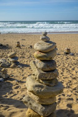 Günbatımında kumlu sahilde, dengeli taşlardan oluşan piramit, Atlantik Okyanusu, Portekiz