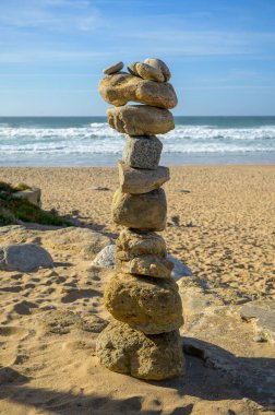 Günbatımında kumlu sahilde, dengeli taşlardan oluşan piramit, Atlantik Okyanusu, Portekiz