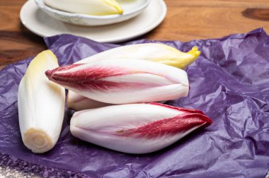 Taze organik Belçika endivi veya acı yeşil ve kırmızı hindiba marulu mor koruma kağıdına yakın.