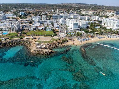 Villalar, tatil beldeleri ve Akdeniz 'deki kumlu incir ağacı plajı, Protaras, Kıbrıs Rum Kesimi yakınlarındaki mavi kristal berrak su üzerindeki hava panoramik manzarası