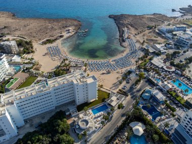 Kıbrıs Rum Kesimi 'nin Ayia Napa plajı yakınlarındaki Akdeniz' de tatil villaları ve tatil beldelerinde havadan panoramik manzara ve mavi kristal berrak su. Deniz tatili.