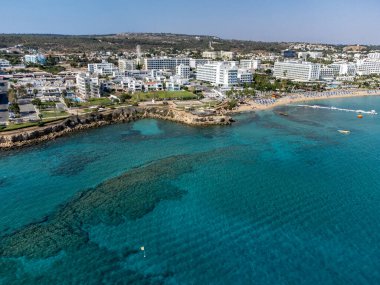 Villalar, tatil beldeleri ve Akdeniz 'deki kumlu incir ağacı plajı, Protaras, Kıbrıs Rum Kesimi yakınlarındaki mavi kristal berrak su üzerindeki hava panoramik manzarası
