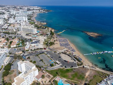 Villalar, tatil beldeleri ve Akdeniz 'deki kumlu incir ağacı plajı, Protaras, Kıbrıs Rum Kesimi yakınlarındaki mavi kristal berrak su üzerindeki hava panoramik manzarası