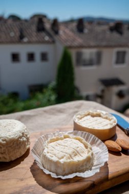 Fransız peynirleri Rocamadour ve Saint-Marcellin güneş ışığında bademlerle zeytin ağacı tahtasında servis edildi.