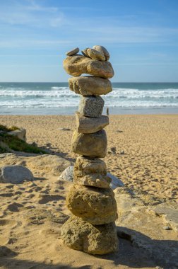 Günbatımında kumlu sahilde, dengeli taşlardan oluşan piramit, Atlantik Okyanusu, Portekiz