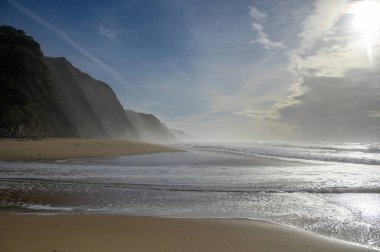 Atlantik Okyanusu 'nda gün batımında Magoito Sahili, Sintra Sahili' nde güzel kumlu plaj, Lizbon Bölgesi, Portekiz, Sintra-Cascais Doğal Parkı 'nın doğal ilgi noktaları.