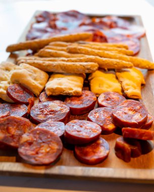 Dilimlenmiş İspanyol mezeli ahşap tabak, sosis, lomo iberico ekmek çubukları, yakın çekim.