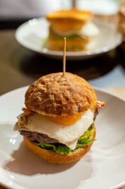 Lezzetli burger, beyaz çıtır yasak, sığır burger, yumurta, yeşil marul ve peynirle yapılır.