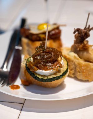 Bask ülkesinin tipik aperatiflerine sahip beyaz tahta, küçük ekmek parçaları, kabak, deniz ürünü, yumurta, peynir içeren pinkhos veya pinktos şişleri, San Sebastian veya Bilbao, İspanya 'da barda servis edilir.