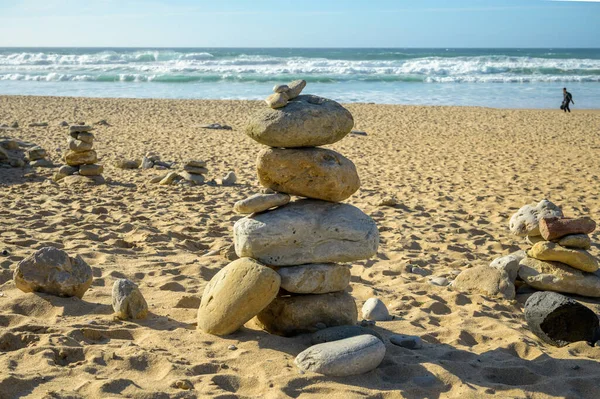 Pyramid from stack balanced stones on sandy beach in sunset, Atlantic ocean, Portugal