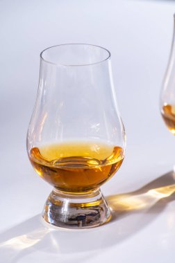 Lale şeklindeki tadım bardağı, bir dirhem İskoç viskisi ya da beyaz arka planda harmanlanmış viskiyle yakın plan.