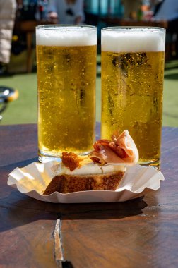 Fresh draught lager or IPA beer is glass served in outdoor cafe with Spanish tapas or pinchos close up, pint of beer close up