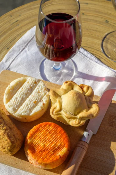 Portuguese food and drink, glass of tawny porto wine,  Codfish croquette pastais de bacalhau, chicken pie, variety of goat, sheep, cow cheeses made with paprika, herbs, made in Portugal
