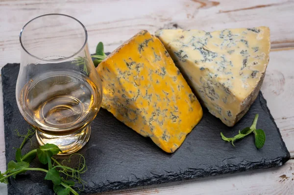 Tasting of Scottish single malt or blended whisky with English cheeses blue stilton and shropshire close up