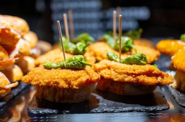 Bask ülkesinin tipik aperatifleri, küçük ekmek parçaları, deniz ürünleri, yumurta, peynir, San-Sebastian veya Bilbao, İspanya 'da barda servis edilen jamon şişleriyle kapatılıyor.