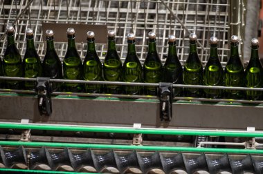 Burgundy, Fransa 'da kremant köpüklü şarap üretimi. Fabrikadaki otomatik güç şişeleme ve mantar hatları.