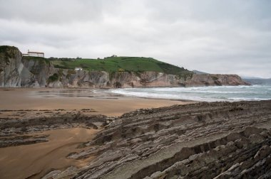 Zumaia 'nın Atlantik kıyısındaki alçak gelgitte, İspanya' nın Bask Bölgesi 'nde dik eğimli sinek jeolojik oluşumuna bakın.
