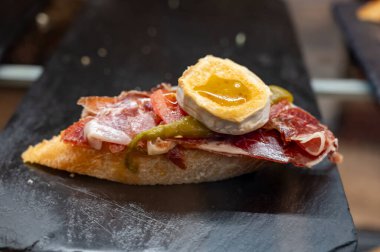 Typical snack of Basque Country, pinchos or pinxtos, small piece of bread with jamon and different toppings, served in bar in San-Sebastian or Bilbao, Spain