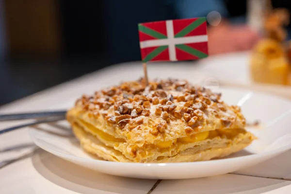 Basque Country food, sweet dessert, puff pastry cake with vanilla cream and hazelnut and flag of Basque Country close up, Spain