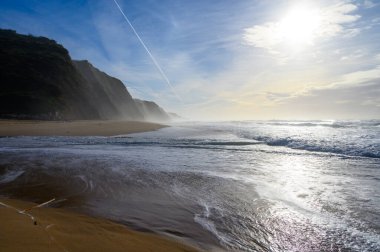 Atlantik Okyanusu 'nda gün batımında Magoito Sahili, Sintra Sahili' nde güzel kumlu plaj, Lizbon Bölgesi, Portekiz, Sintra-Cascais Doğal Parkı 'nın doğal ilgi noktaları.