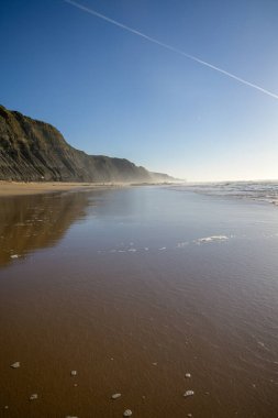 Atlantik Okyanusu 'ndaki Magoito Sahili, Sintra kıyısındaki güzel kumlu sahil gelgit sırasında, Lizbon bölgesi, Portekiz, Sintra-Cascais Doğal Parkı' nın doğal ilgi noktaları.