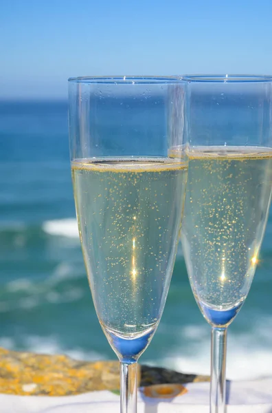 Glasses of champagne sparkling wine and sunny view on blue Atlantic ocean, Lisbon area, Portugal