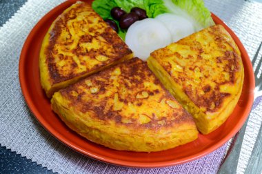 Spanish vegetarian food, portion of homemade tasty potato omelette tortilla de patatas with onion served on terrace in morning sunlights