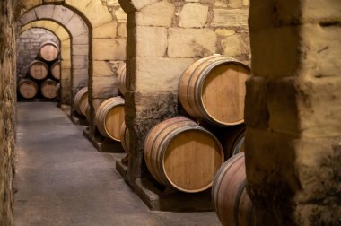Old french oak wooden barrels in underground cellars for wine aging process, wine making in La Rioja region, Spain