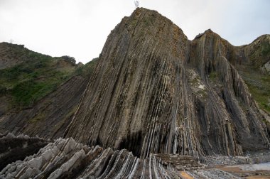 Zumaia 'nın Atlantik kıyısındaki alçak gelgitte, İspanya' nın Bask Bölgesi 'nde dik eğimli sinek jeolojik oluşumuna bakın.