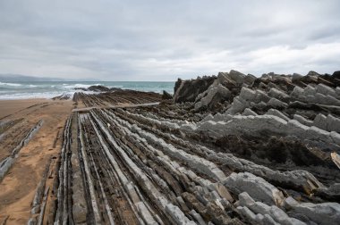 Zumaia 'nın Atlantik kıyısındaki alçak gelgitte, İspanya' nın Bask Bölgesi 'nde dik eğimli sinek jeolojik oluşumuna bakın.