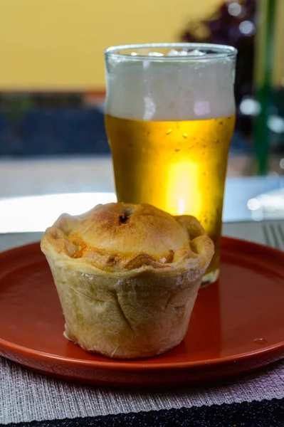 Traditional street food in England, glass of fresh lager beer and stuffed baked pie with pork meat