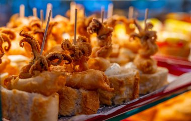 Bask ülkesinin tipik aperatifleri, küçük ekmek parçaları, deniz ürünleri, bebek ahtapot, peynir, San-Sebastian veya Bilbao, İspanya 'da barda sunulan jamon şiş ya da pinkholar, yakın çekim.