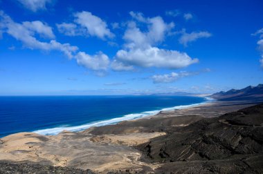 Fuerteventura, Kanarya Adaları 'ndaki sıradağların arkasına gizlenmiş altın kumlu, uzun kahve plajına ulaşmak zor.