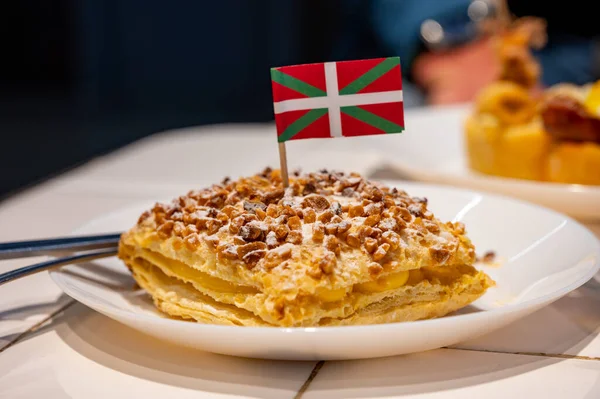 Basque Country food, sweet dessert, puff pastry cake with vanilla cream and hazelnut and flag of Basque Country close up, Spain