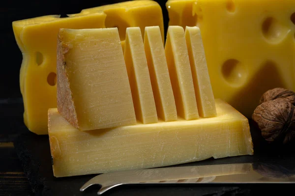 Assortment of Swiss cheeses Emmental or Emmentaler medium-hard cheese with round holes, Gruyere, appenzeller used for traditional cheese fondue and gratin on dark background