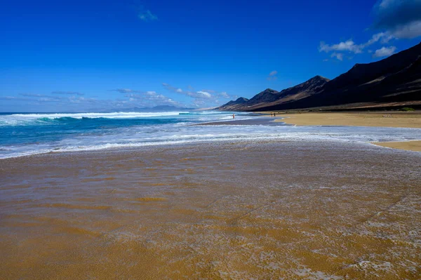 Fuerteventura, Kanarya Adaları 'ndaki sıradağların arkasına gizlenmiş altın kumlu, uzun kahve plajına ulaşmak zor.