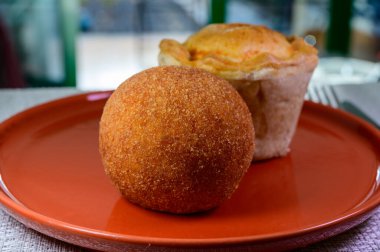 Traditional street food in UK, stuffed fried Scotch eggs with breadcrumbs and baked pie with pork meat close up