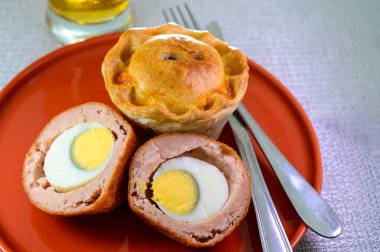 Traditional street food in UK, stuffed fried Scotch eggs with breadcrumbs and baked pie with pork meat close up