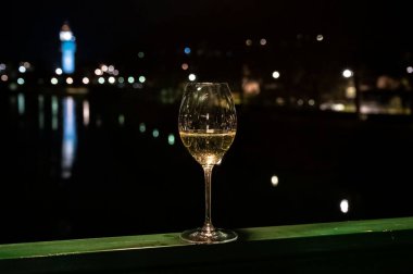 Tasting of french sparkling white wine with bubbles champagne outdoor at night with view on Marne river and lights of Epernay city in winter, France