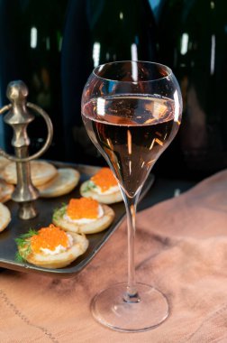Tasting of rose Champagne sparkling wine with red caviar in cellars of gran cru wine house in Epernay, wine tour in Champagne, France, magnum bottles on background