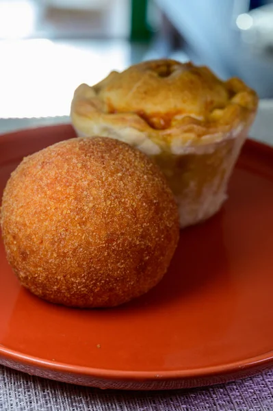 Traditional street food in UK, stuffed fried Scotch eggs with breadcrumbs and baked pie with pork meat close up