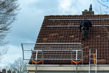 Bulutlu kış gününde evin çatısına güneş panelleri kurulması, Avrupa 'da yeşil enerji