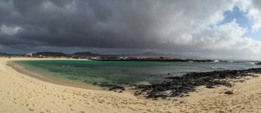 Beyaz kum, mavi su ve fırtınalı bulutlar La Concha sahilinde, El Cotillo sörfçülerinin köyü, Fuerteventura, Kanarya adaları, İspanya