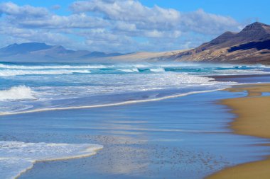 Fuerteventura, Kanarya Adaları 'ndaki sıradağların arkasına gizlenmiş altın kumlu, uzun kahve plajına ulaşmak zor.