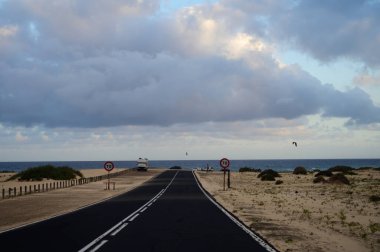 Corallejo sahilinin yakınlarındaki siyah kumlu kumsallarda Fuerteventura, Kanarya Adaları, İspanya 'daki renkli günbatımında araba sürüyorum.