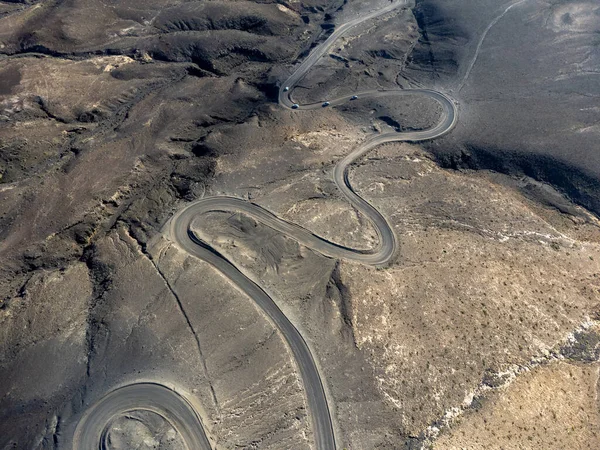 stock image Dangerous narrow dirty road to golden sandy Cofete beach hidden behind mountain range on Fuerteventura, Canary islands, Spain, aerial view