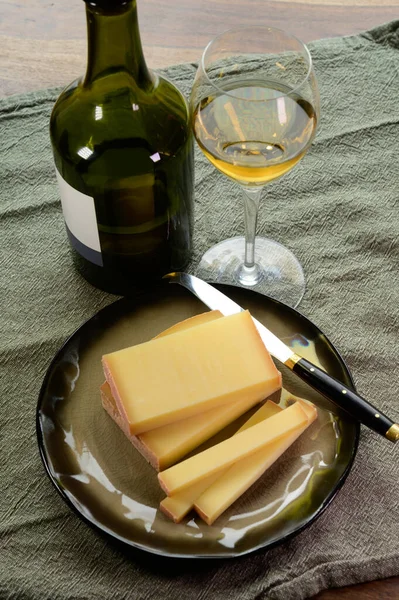 Wine and cheese pairing, local Comte cheese produced in the Franche Comte region and glass and clavelin bottle special and characteristic yellow wine vin jaune from Jura region, France